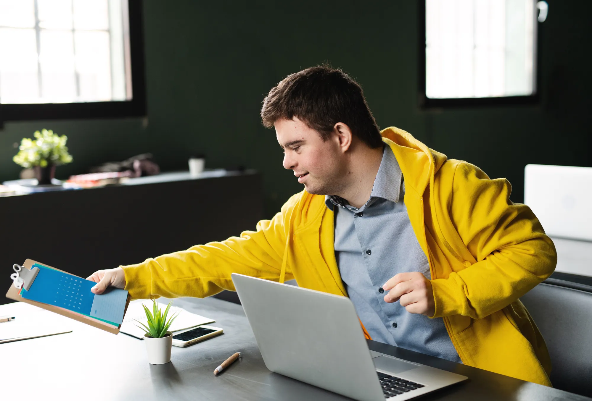 Junger Mann mit Trisomie 21 arbeitet am Laptop